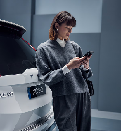 Volvo driver checking their phone next to their car